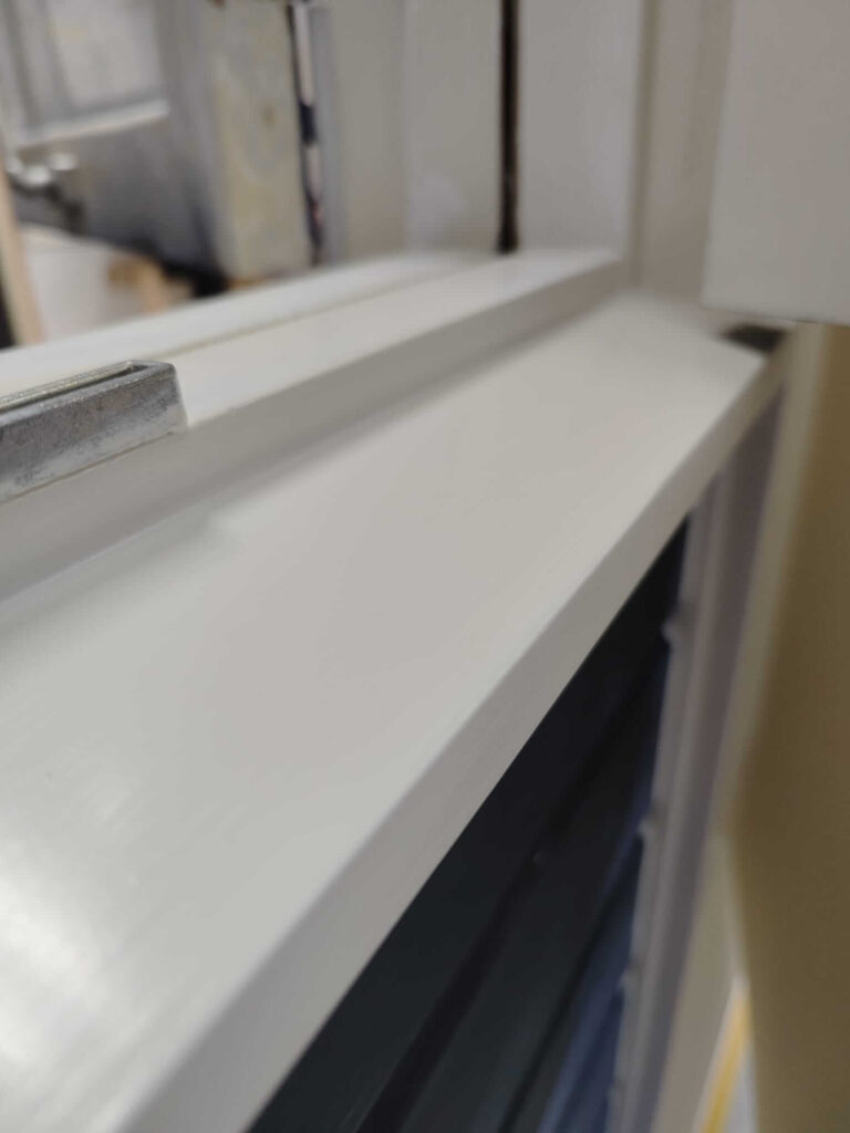 Deel van een kozijn welke is afgelakt met een lichte kleur op de vakschool