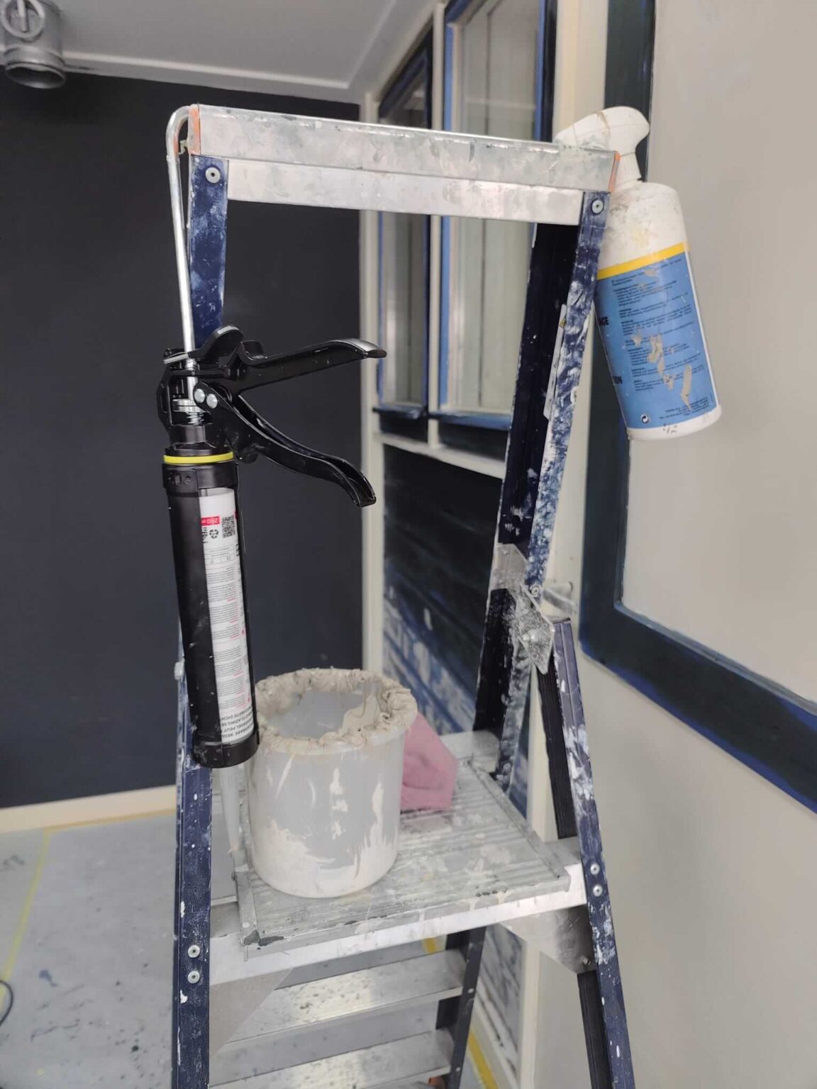 Voorbereiding voor het glaskitten op de vakschool: kitspuit en gereedschap op een trap