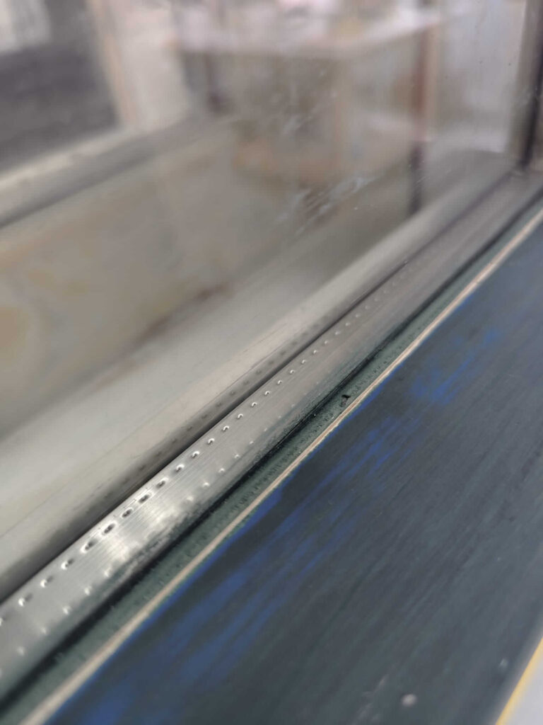 Raamkozijn detail na het verwijderen van oude glaskit tijdens de schildersopleiding