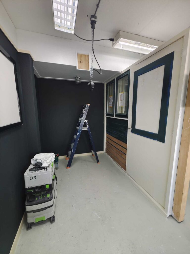 Schilder in opleiding praktijkhok met geschuurde houten rabatdelen bij Faber vakschool