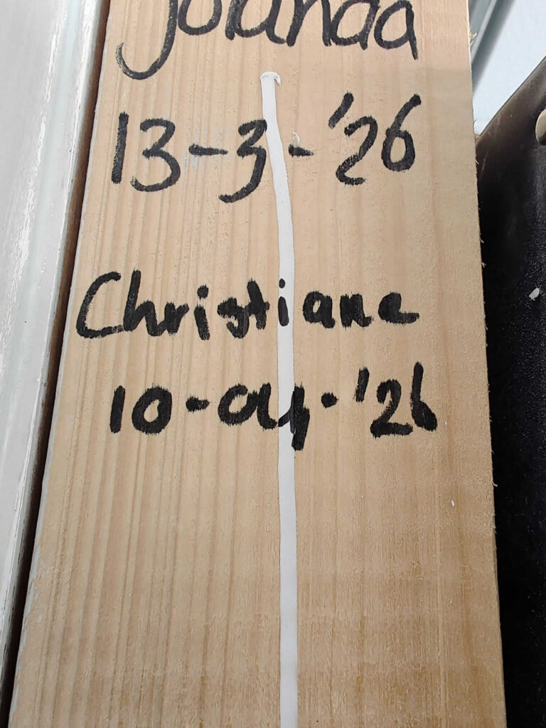 Christiane's afscheid op de vakschool: haar naam en de datum van de laatste cursusdag geschreven op een houten onderdeel in haar praktijkruimte.