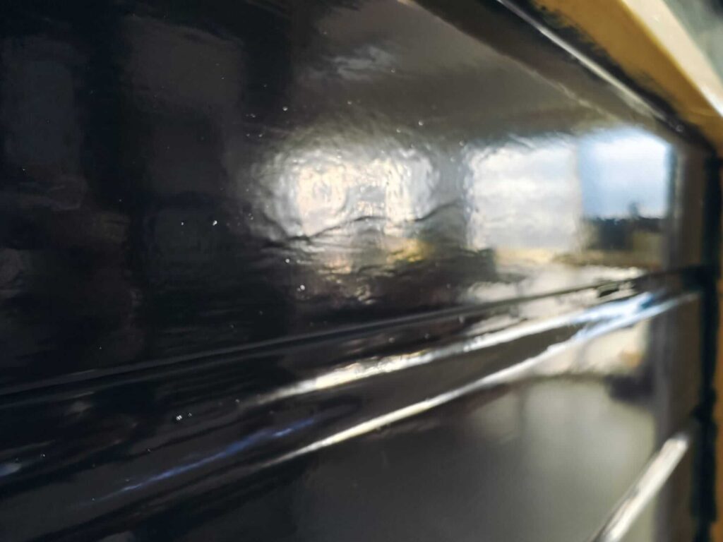 Detailopname van een blauw geschilderd rabatdeel met een 'gordijntje' (zakkende verf) door het te dik aanbrengen van de grondverf.