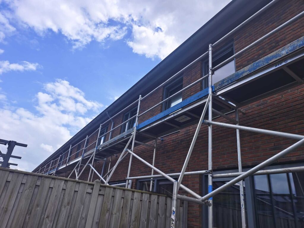 Steiger bij een woning tijdens schilderwerk aan de bovenzijde van de kozijnen - Stage Chris