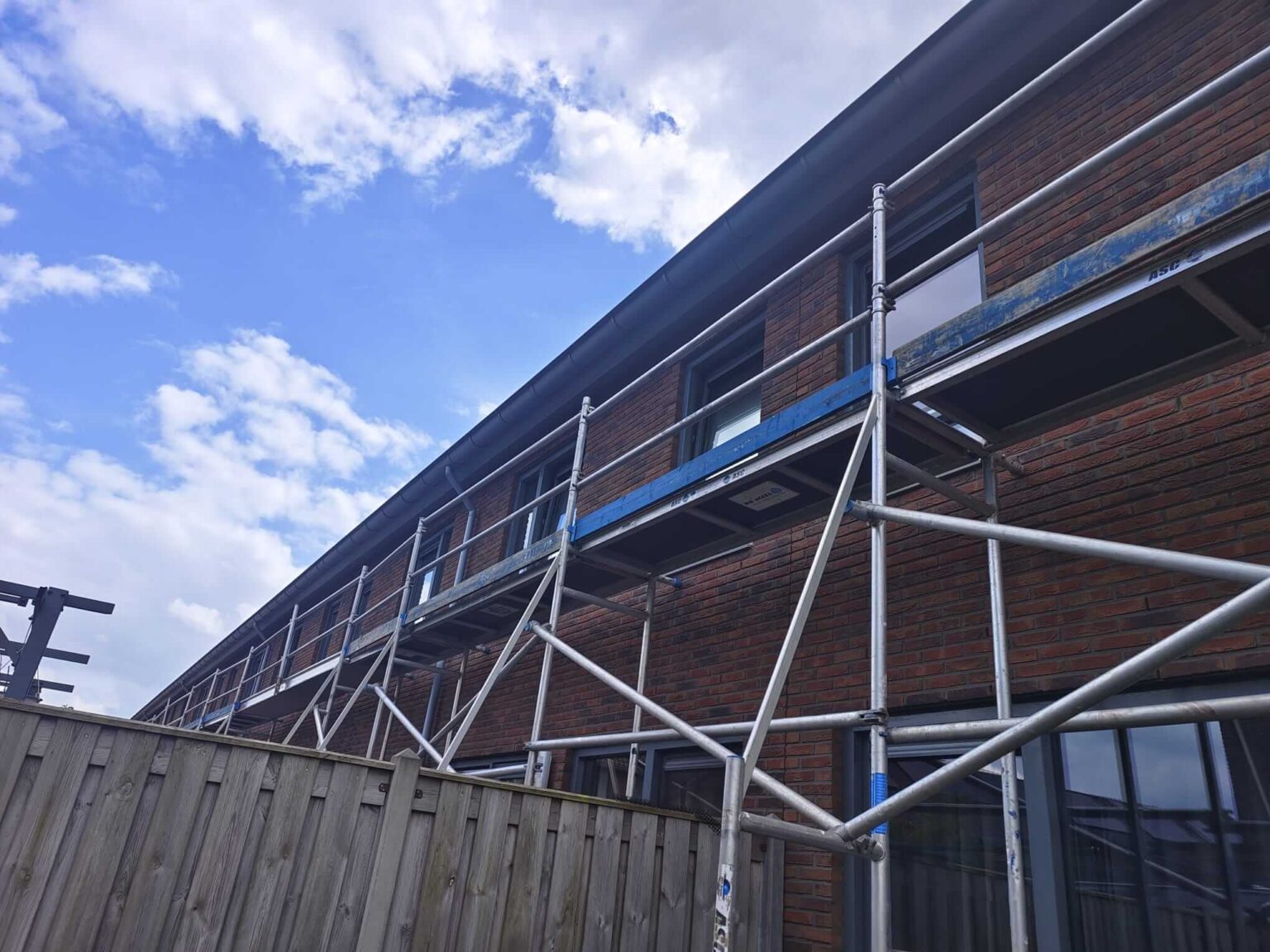 Steiger bij een woning tijdens schilderwerk aan de bovenzijde van de kozijnen - Stage Chris